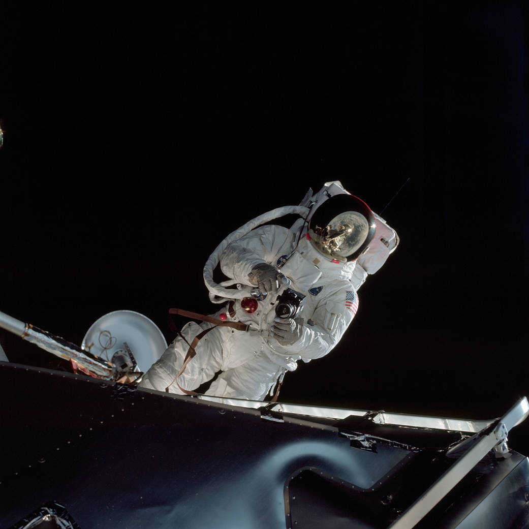 Astronaut Russell L. Schweickart, lunar module pilot, operates a 70mm Hasselblad camera during his extravehicular activity on the fourth day of the Apollo 9 earth-orbital mission. The Command/Service Module and the Lunar Module 3 "Spider" are docked. This view was taken form the Command Module "Gumdrop". Schweickart, wearing an Extravehicular Mobility Unit (EMU), is standing in "golden slippers" on the Lunar Module porch. On his back, partially visible, are a Portable Life Support System (PLSS) and an Oxygen Purge System (OPS). Film magazine was A,film type was SO-368 Ektachrome with 0.460 - 0.710 micrometers film / filter transmittance response and haze filter,80mm lens. Astronaut Russell L. Schweickart, lunar module pilot, operates a 70mm Hasselblad camera during his extravehicular activity on the fourth day of the Apollo 9 earth-orbital mission. The Command/Service Module and the Lunar Module 3 "Spider" are docked. This view was taken form the Command Module "Gumdrop". Schweickart, wearing an Extravehicular Mobility Unit (EMU), is standing in "golden slippers" on the Lunar Module porch. On his back, partially visible, are a Portable Life Support System (PLSS) and an Oxygen Purge System (OPS). Film magazine was A,film type was SO-368 Ektachrome with 0.460 - 0.710 micrometers film / filter transmittance response and haze filter,80mm lens.