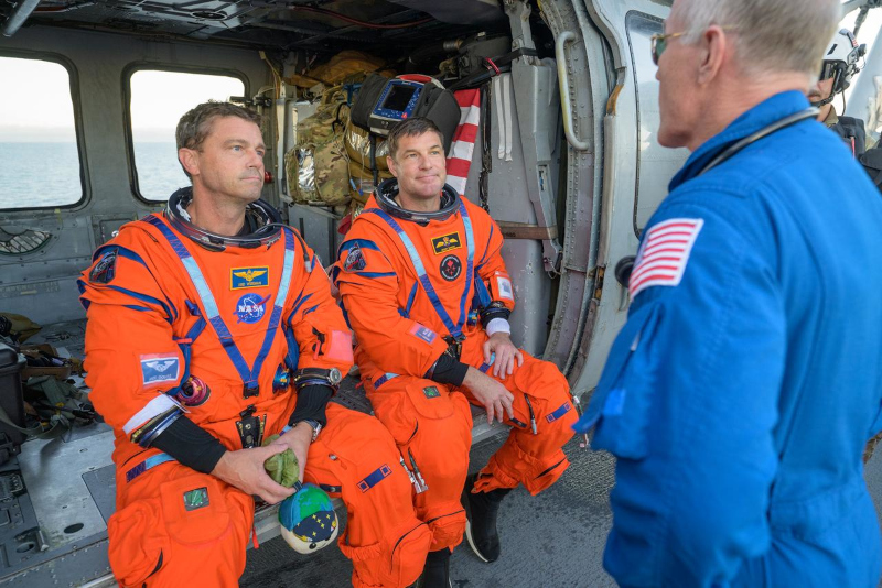 Richard Wiseman and Jeremy Hansen talk with a NASA Flight Surgeon onboard the helicopter on the flight deck of the recovery ship