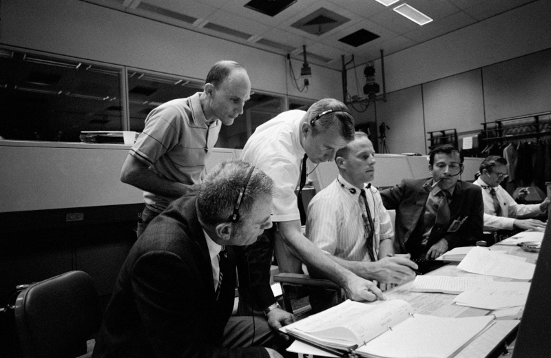Slayton and several astronauts are gathered at the consoles in mission control during the Apollo 13 crisis in April 1970